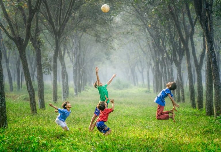 Kids Storage - four boy playing ball on green grass