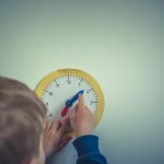 Smart Nursery - person in blue long sleeve shirt holding white round analog wall clock